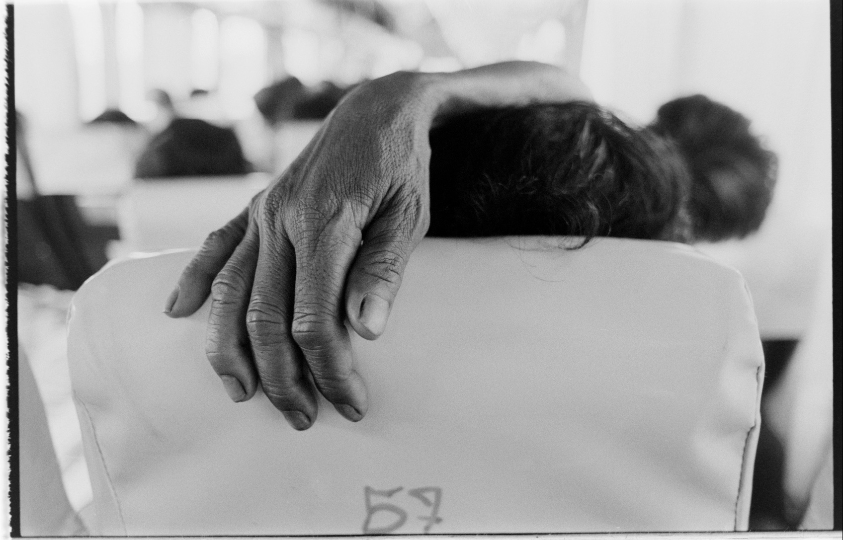 A fellow traveller's hand behind their seat's headrest on a coach, travelling from Chiang Mai to Bangkok.
